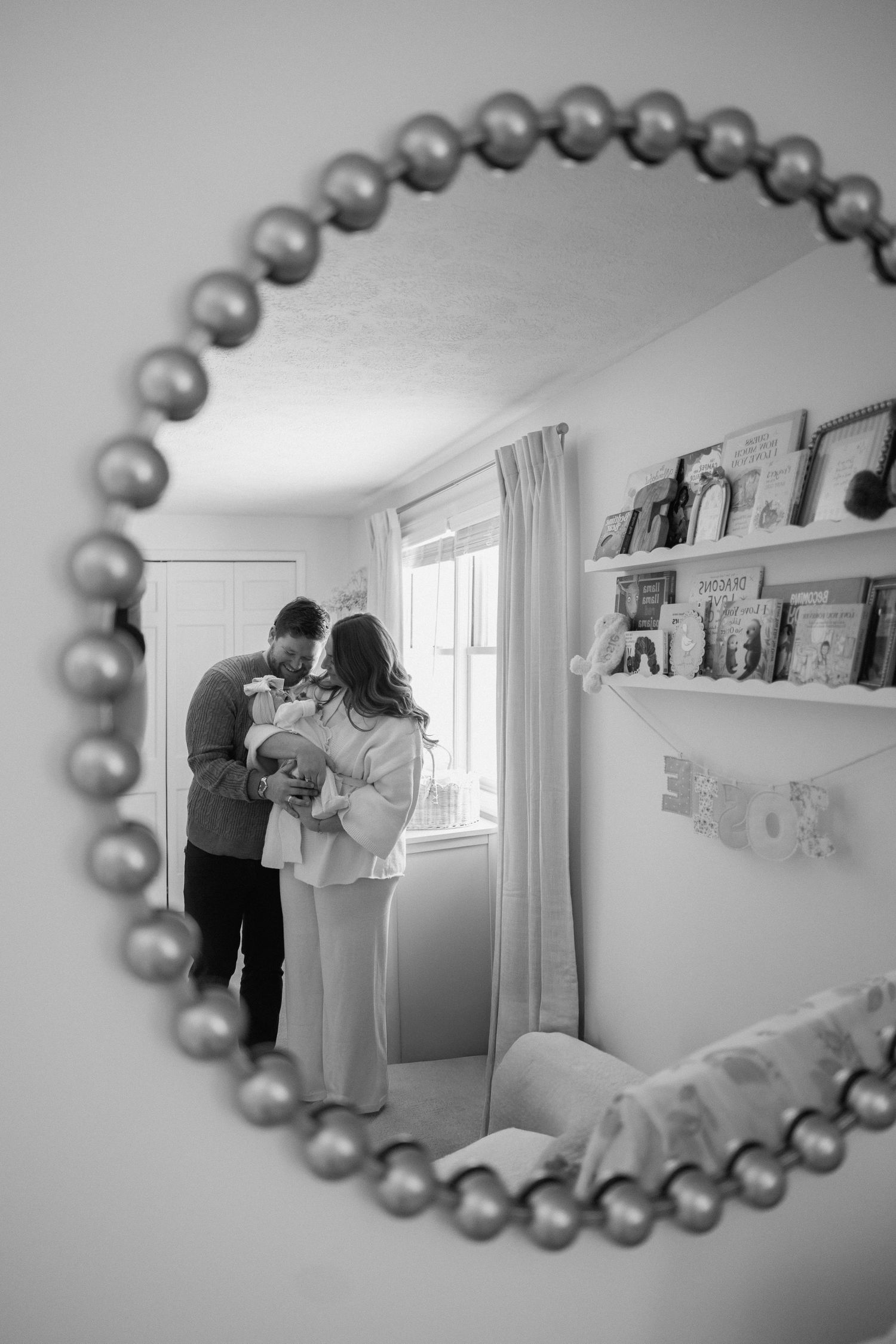 A series of black and white photos reflected in a beaded oval mirror showing a wedding preparation scene.