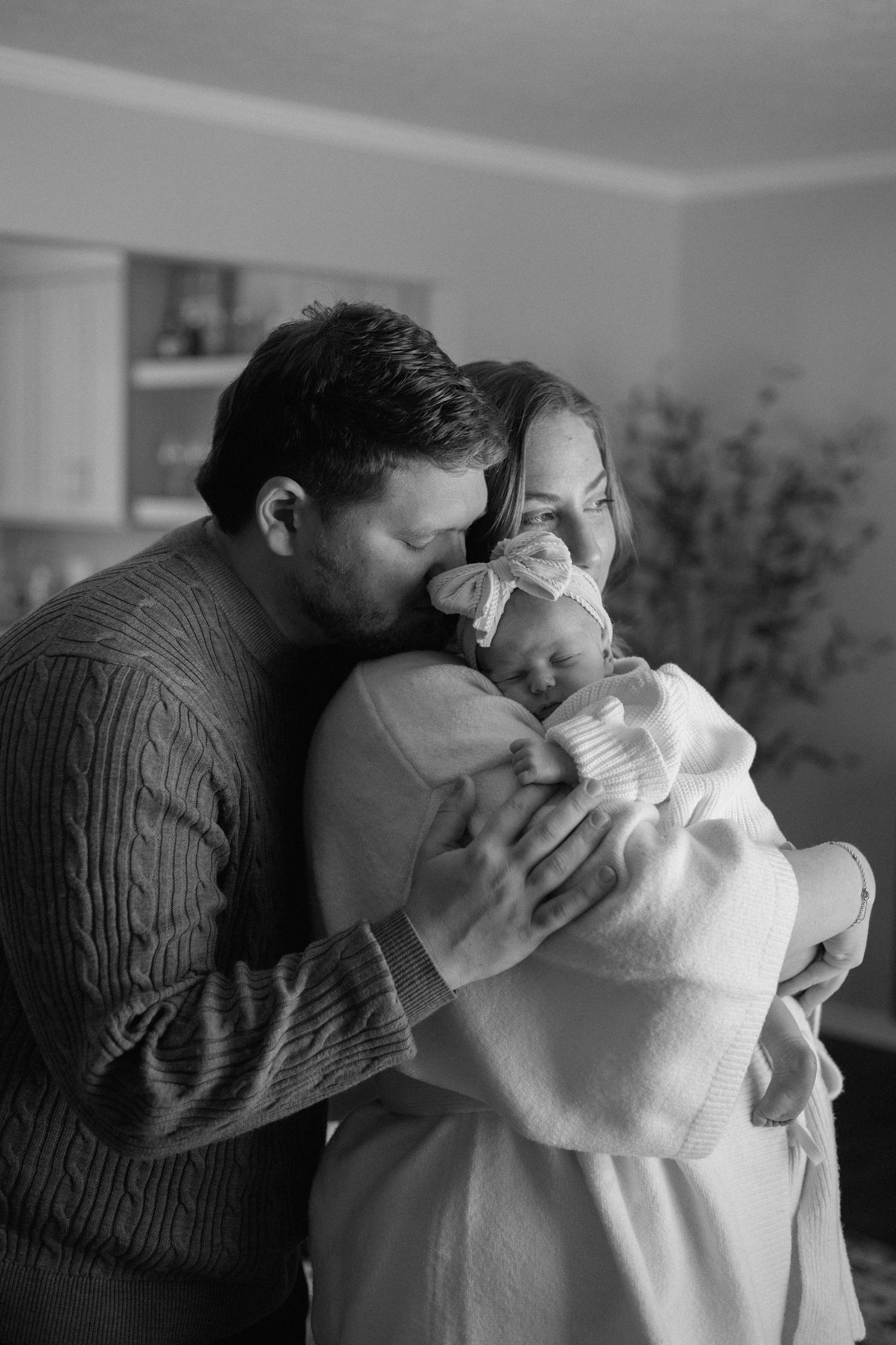 Black and white photo of tender moment with baby being held and embraced.