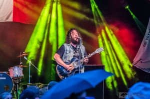 Musician on stage singing and playing guitar. Jeff Fevens Photography.