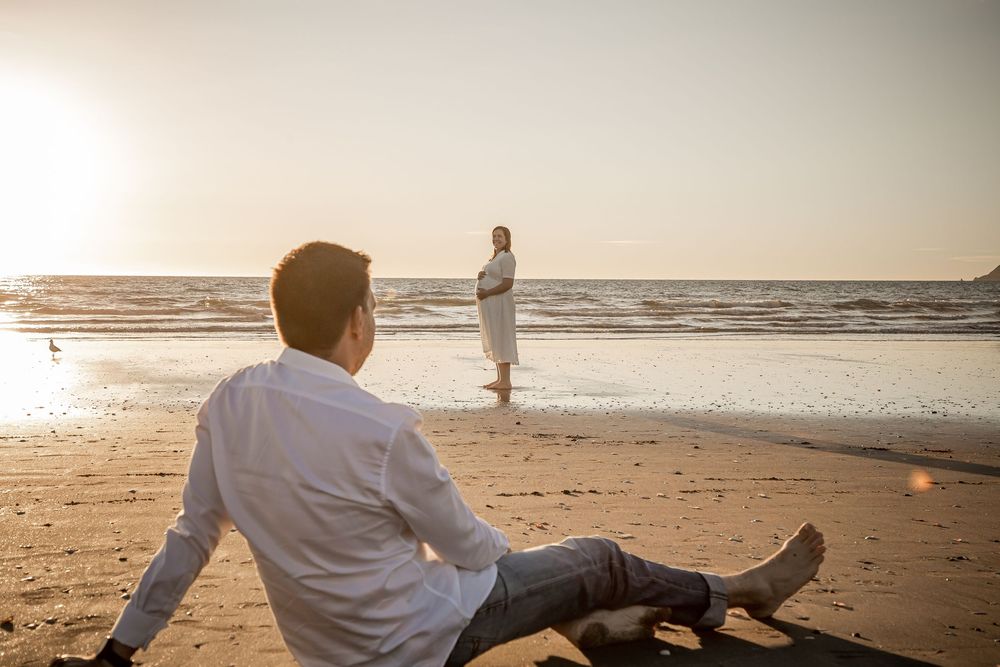 Person walking along a serene beach at sunset with waves gently rolling onto the shore.