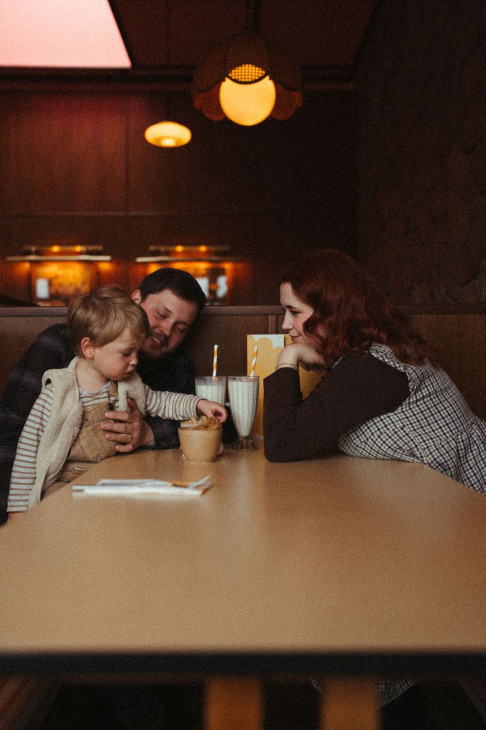 Family sharing drinks and quality time together at a cozy restaurant booth with warm lighting.