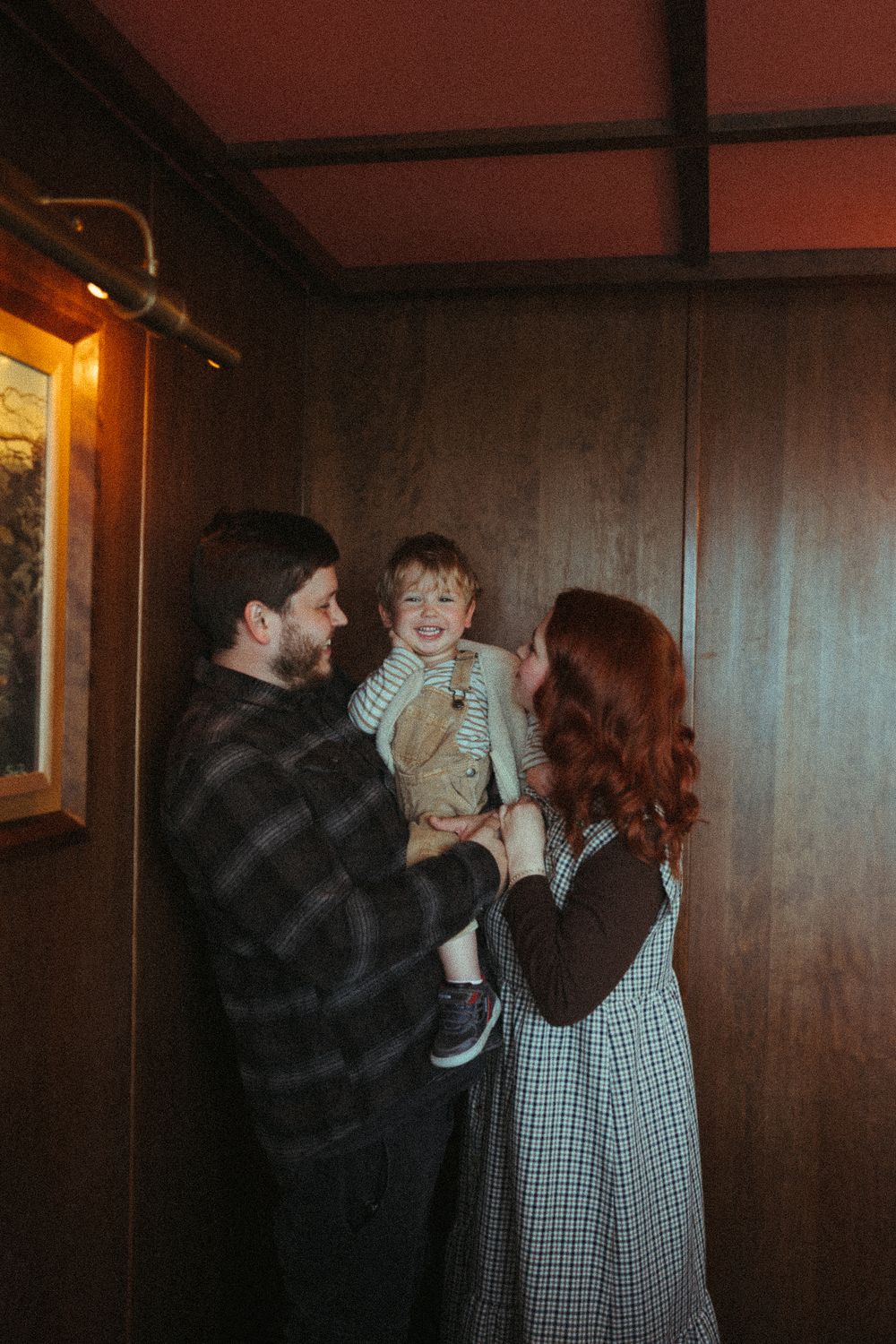Candid family moment captured in a dimly lit restaurant interior with wood paneled walls.