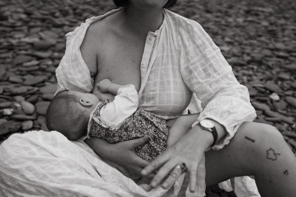 Intimate black and white portrait of parent and baby bonding on rocky ground.