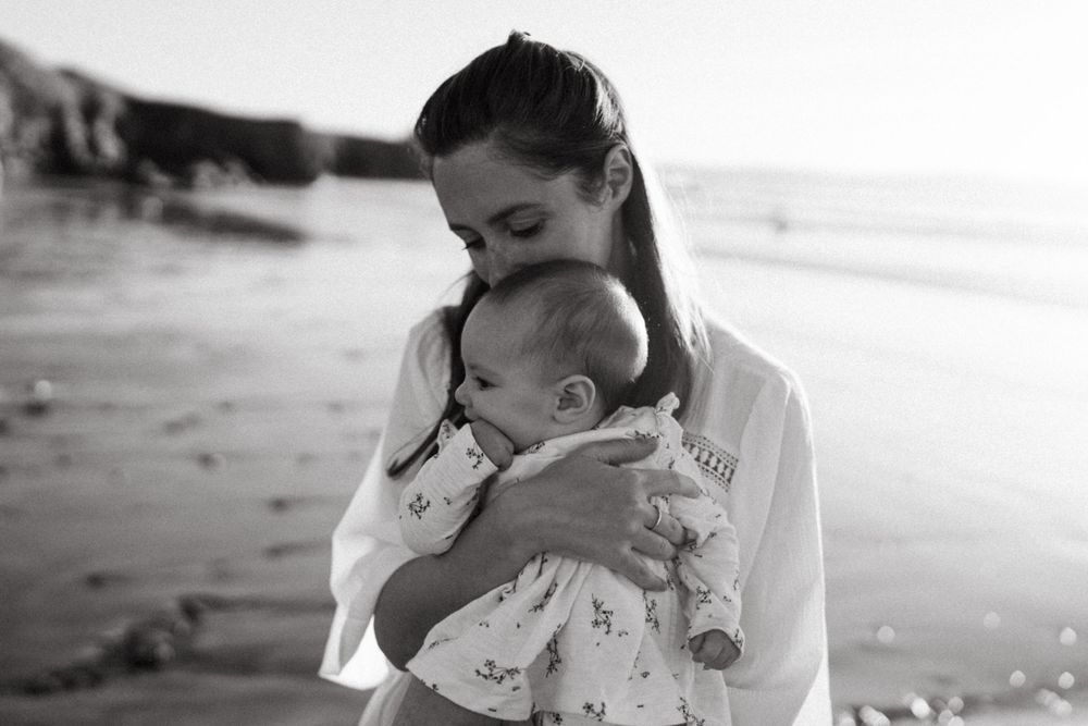 Tender moment between parent and child on a misty beach in black and white.