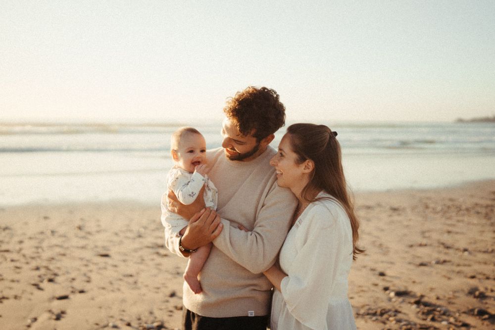 Family sharing intimate moment together on sunny beach at golden hour.