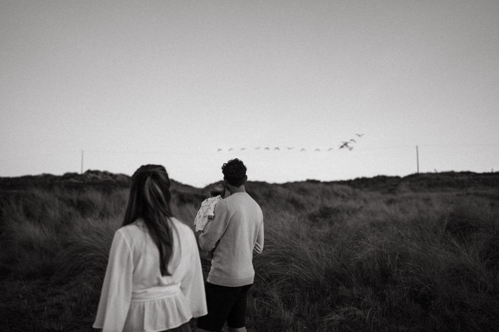 Couple standing together on grassy hillside in black and white.