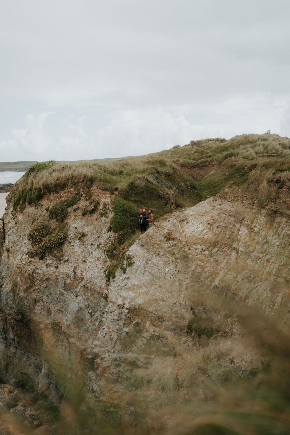 Dramatic coastal cliff landscape with rugged terrain against an overcast sky.