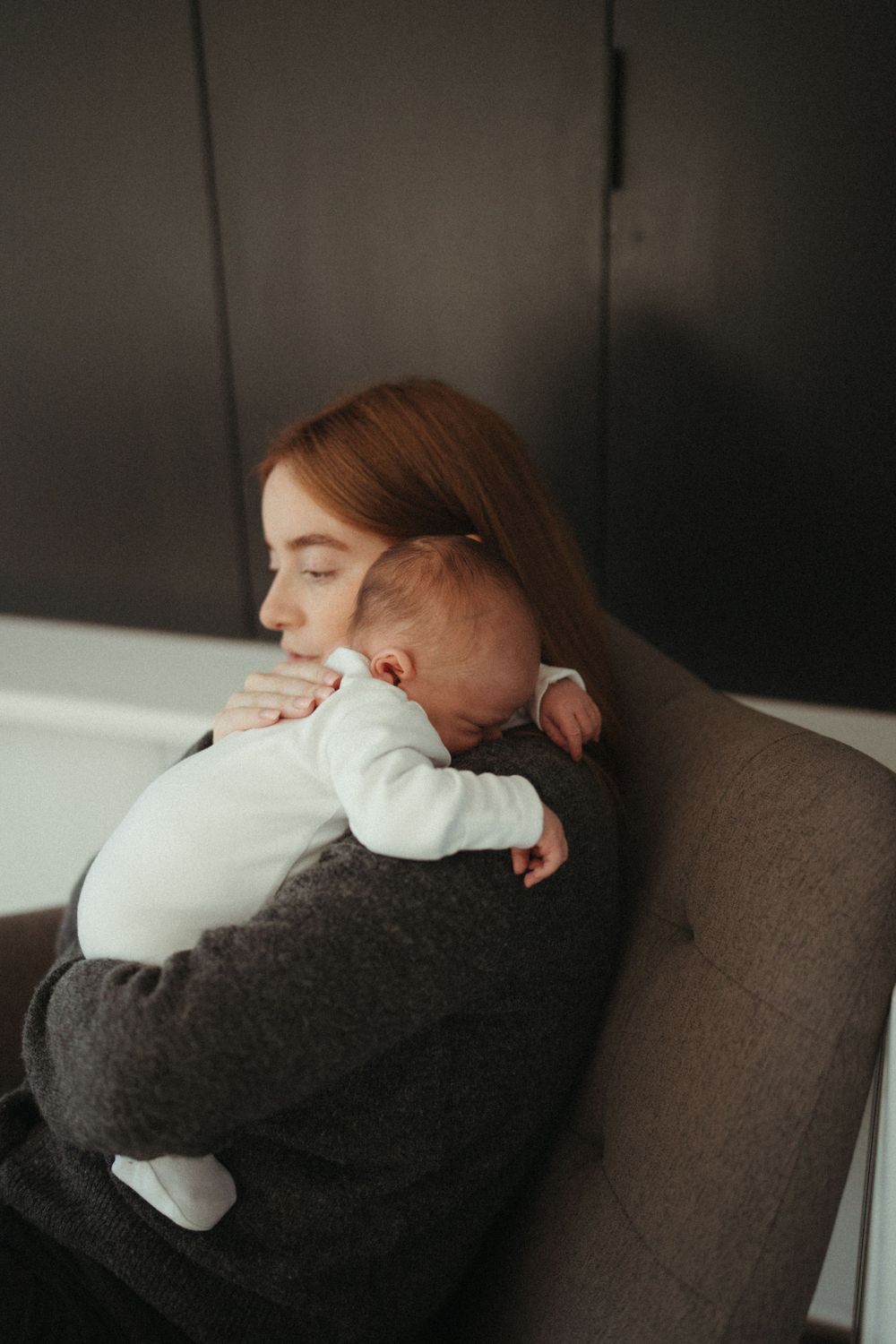 Quiet moment of parent and baby resting together in cozy armchair.