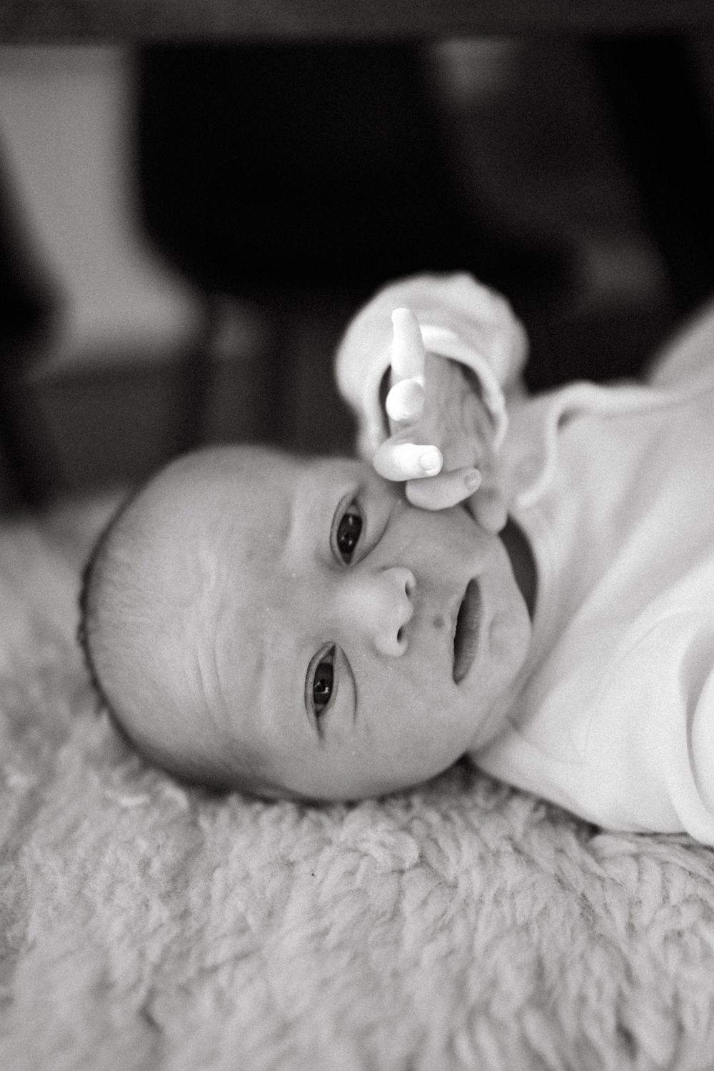 Close-up black and white portrait of baby lying on soft furry blanket.