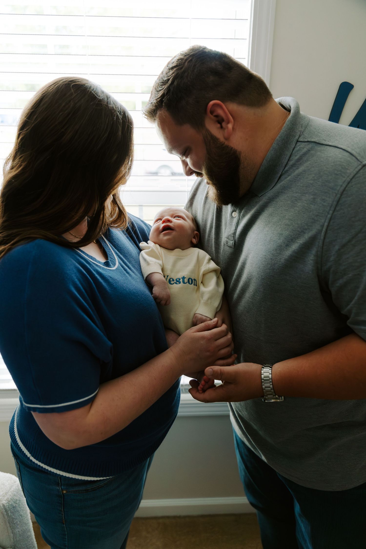 A series of intimate family moments captured in a nursery showing parents bonding with their newborn.