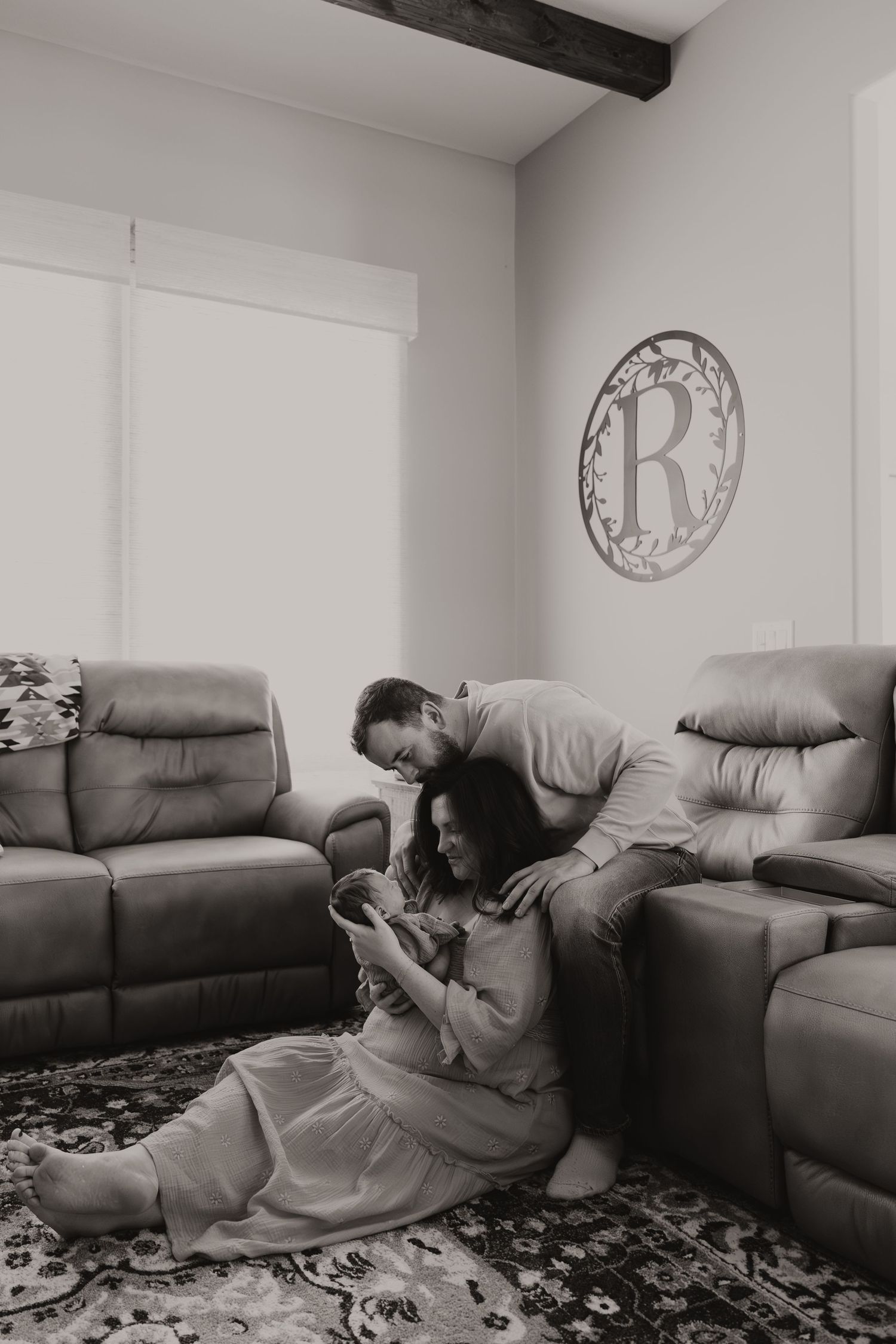 A person is lying on a gray couch in a living room with white walls and decorative wall art.