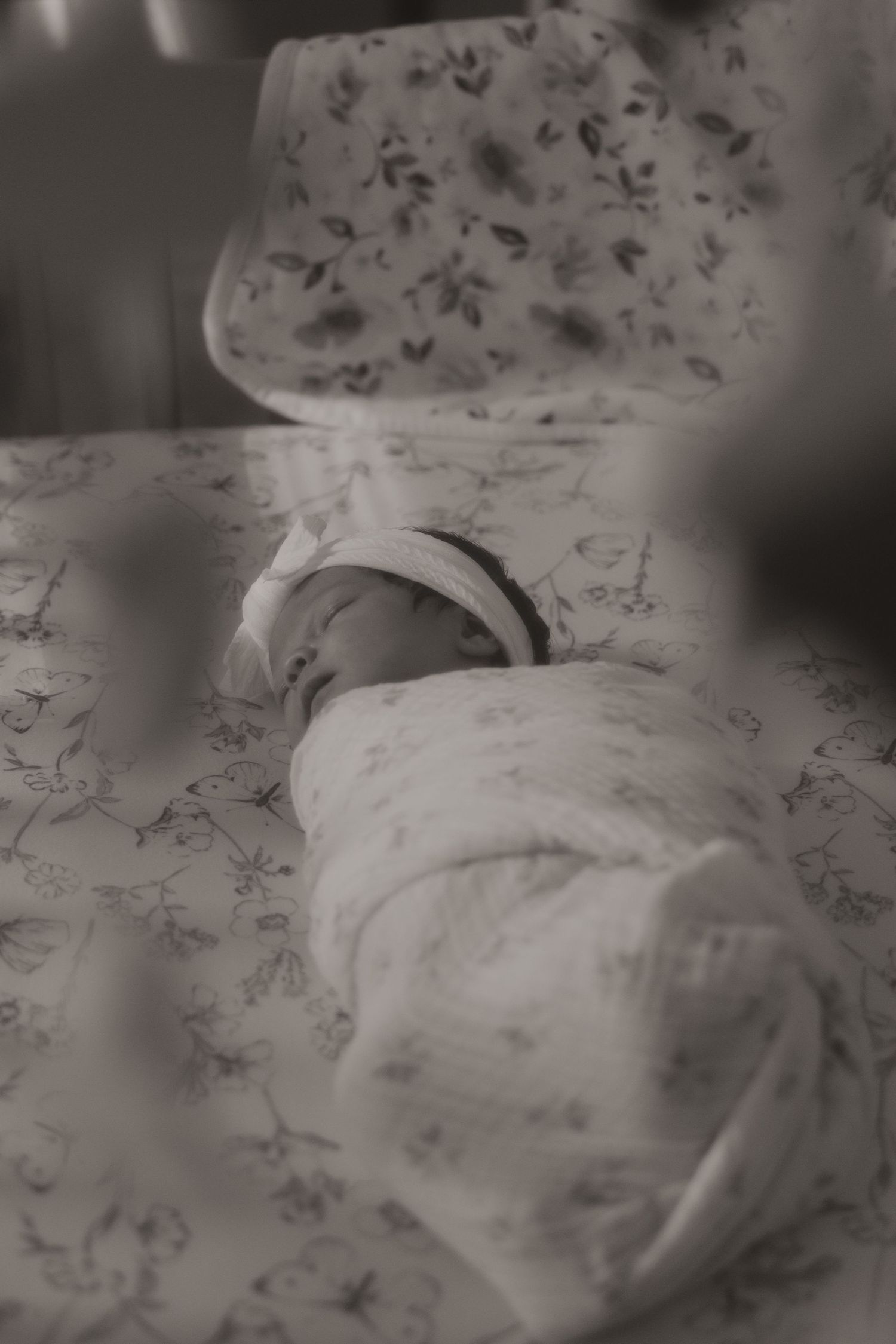 A series of black and white photos showing a person sleeping peacefully on a floral patterned bedspread.