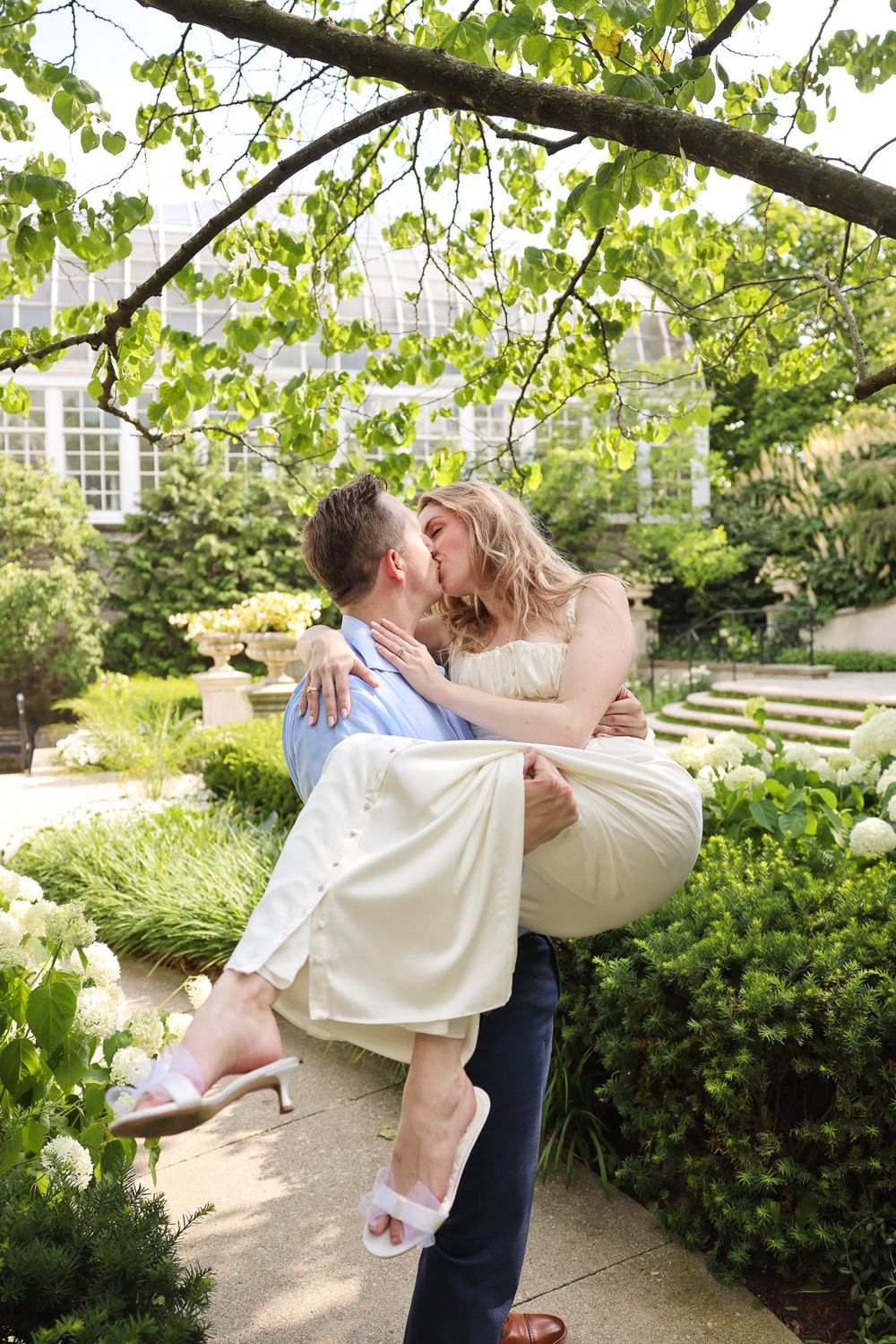 Romantic garden wedding scene with couple sharing intimate moment among green foliage.