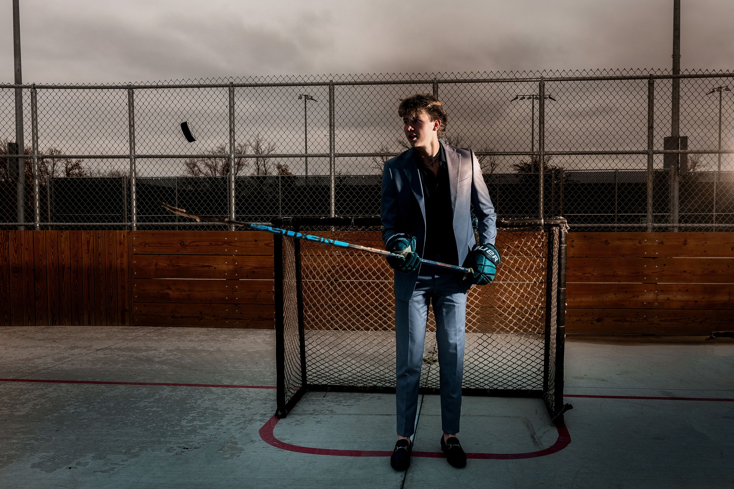 Person in blue jeans stands alone on an empty basketball court at dusk.