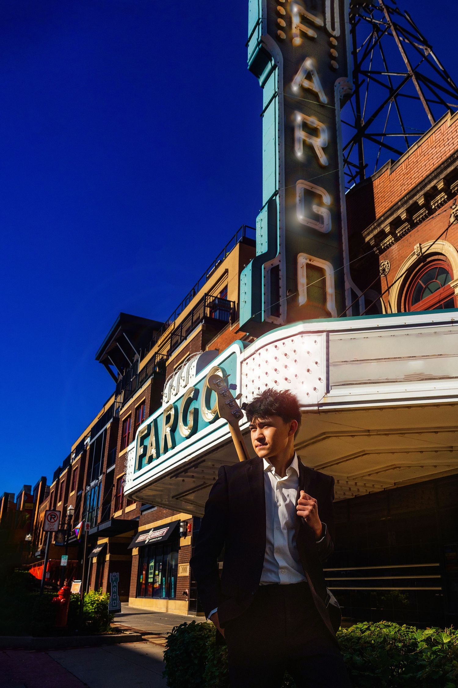 Young man in suit stands before the iconic Fargo Theatre marquee under a vivid blue sky.