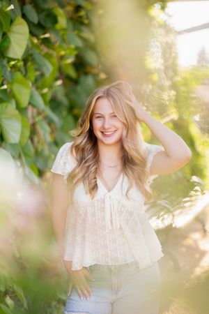 A dreamy outdoor portrait session in soft natural light with green foliage creating a romantic ethereal atmosphere.