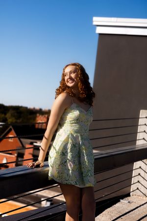 A series of photos showing someone in a pale yellow dress posing on a balcony against a bright blue sky.