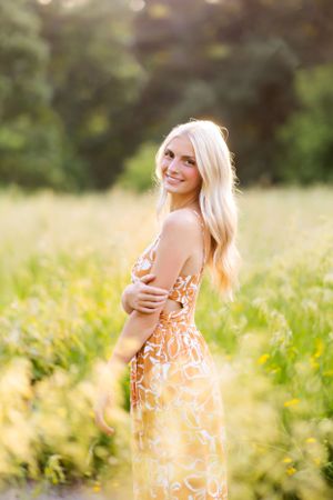 Young woman in floral dress twirling through a sun-drenched meadow.