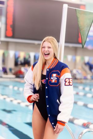 Athletic varsity jacket displayed at an indoor swimming pool with blue lanes.