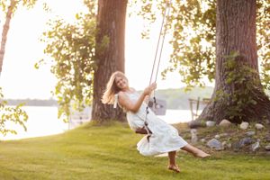 Whimsical portrait session featuring a white dress and tree swing at sunset.