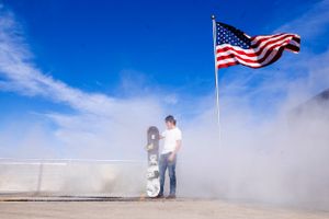 American flags wave against a bright blue sky during a patriotic ceremony.