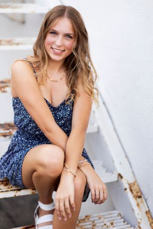 A photo session featuring summer portraits on white stairs with a floral navy blue dress.