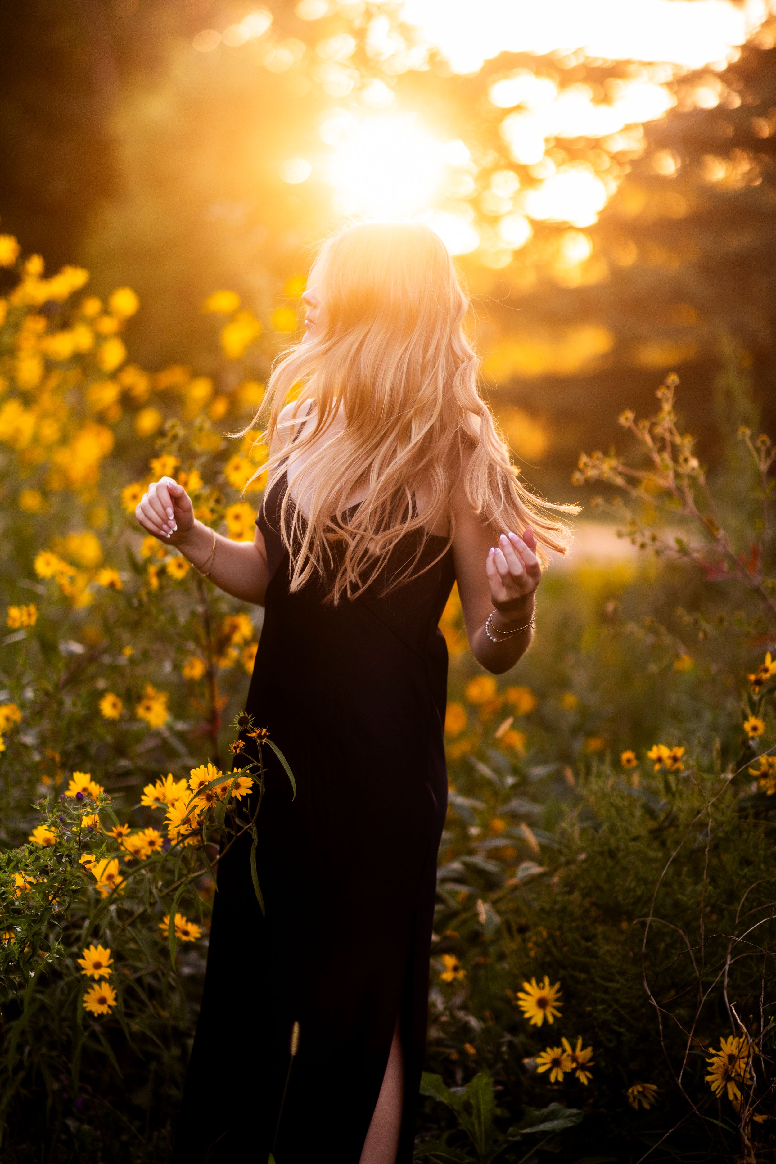 Dancing figure silhouetted against golden sunset light in field of yellow wildflowers.