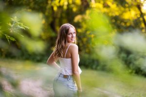 Artistic outdoor portraits captured through blurred greenery and foliage.