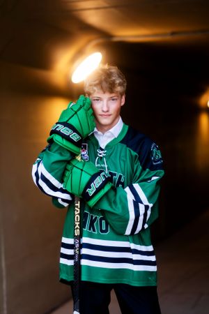 Sports portrait featuring green and white hockey jersey in dramatic lighting.