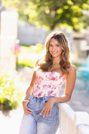 Summer fashion portrait with floral corset top and denim in golden sunlight.