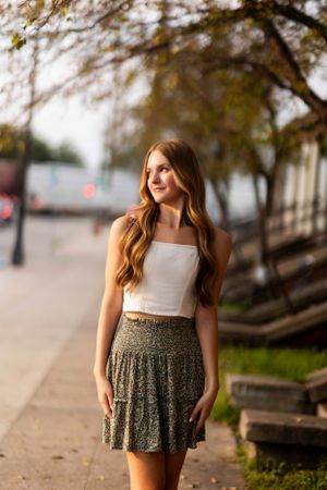 A floral print skirt twirls against a blurred urban background with trees.