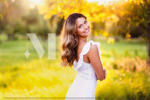 A white summer dress stands out against a dreamy golden bokeh background in a sunlit outdoor setting.