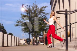 Parkour athlete in red performs athletic jumps across urban architecture and concrete walls.