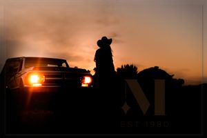 Silhouettes of vehicles against dramatic orange sunset sky.