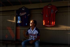 Row of sports jerseys displayed in a dark locker room or retail environment.