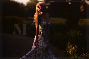 A figure in a floral dress poses in a dreamy golden sunset setting.