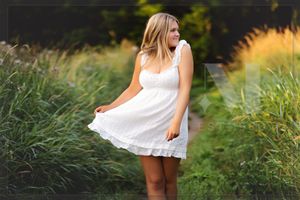 A woman in white dress twirls gracefully in a sun-drenched meadow filled with tall grass and golden light.