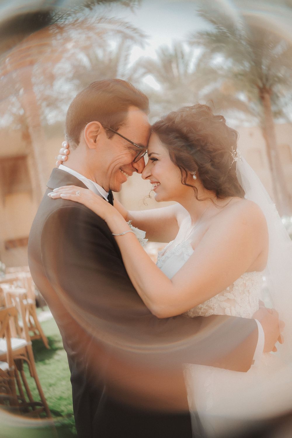 Romantic wedding couple embraces in soft dreamy light during outdoor garden ceremony.