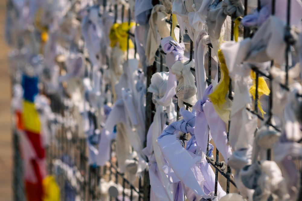 Personal messages and prayers written on white paper ribbons tied to a fence with yellow and red ribbons also visible in Sri Lanka.