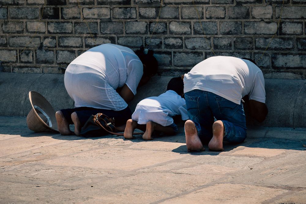 A family bending down in prayer to honour the Buddha in Sri Lanka.