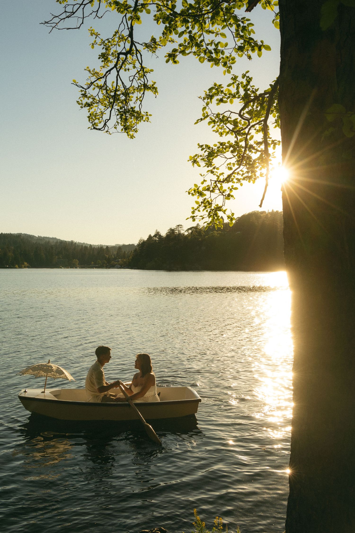 A couple sits together in a small boat on a serene lake at sunset. The notebook Documentary photographer