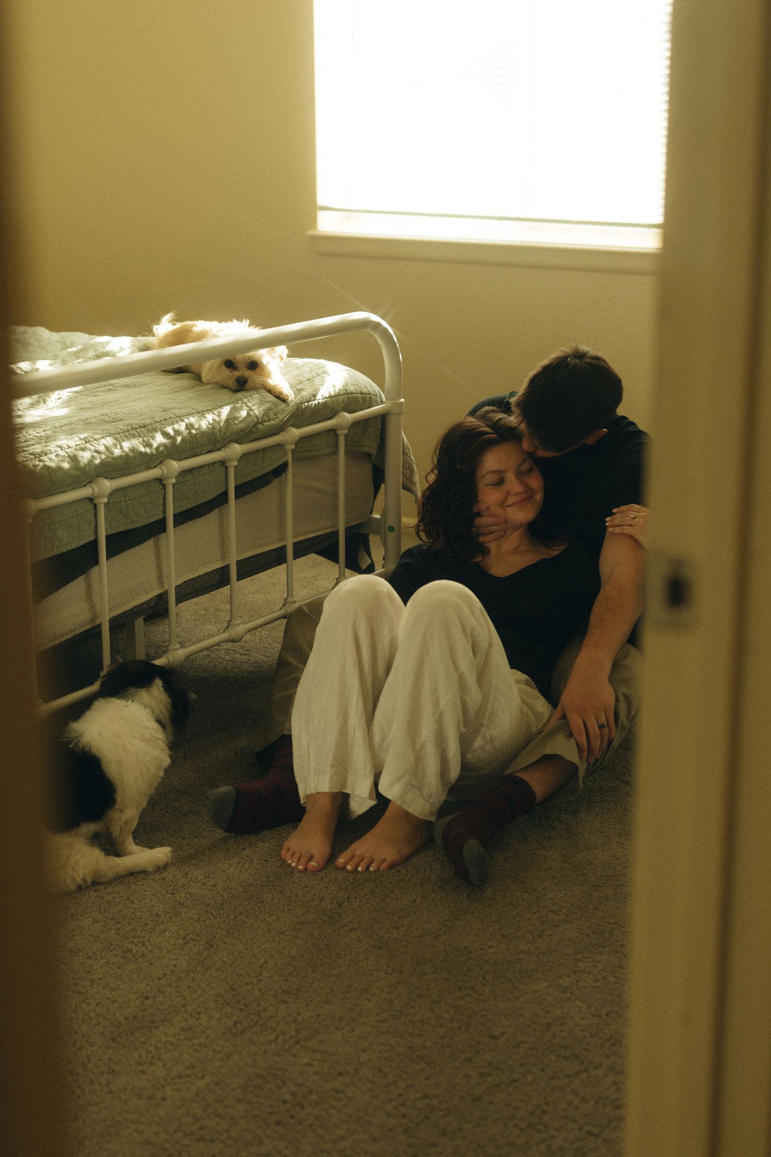 Cozy indoor lifestyle photo with a dogs walking past in the background. In home couple session Documentary photographer