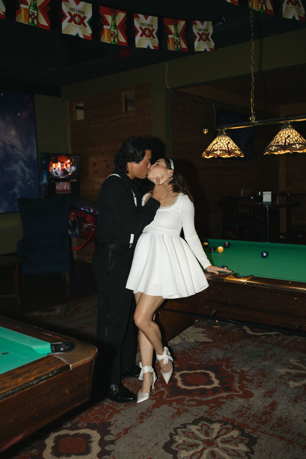 A couple dancing by pool tables in a bar with decorative wall patterns. Documentary photographer