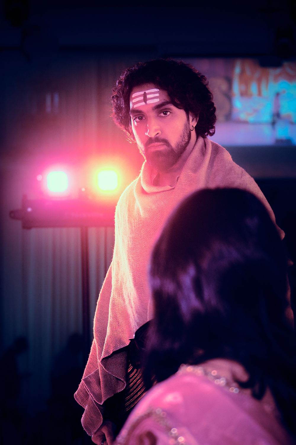 Concert performer in a dark venue illuminated by vibrant pink stage lights creating a moody atmospheric scene.