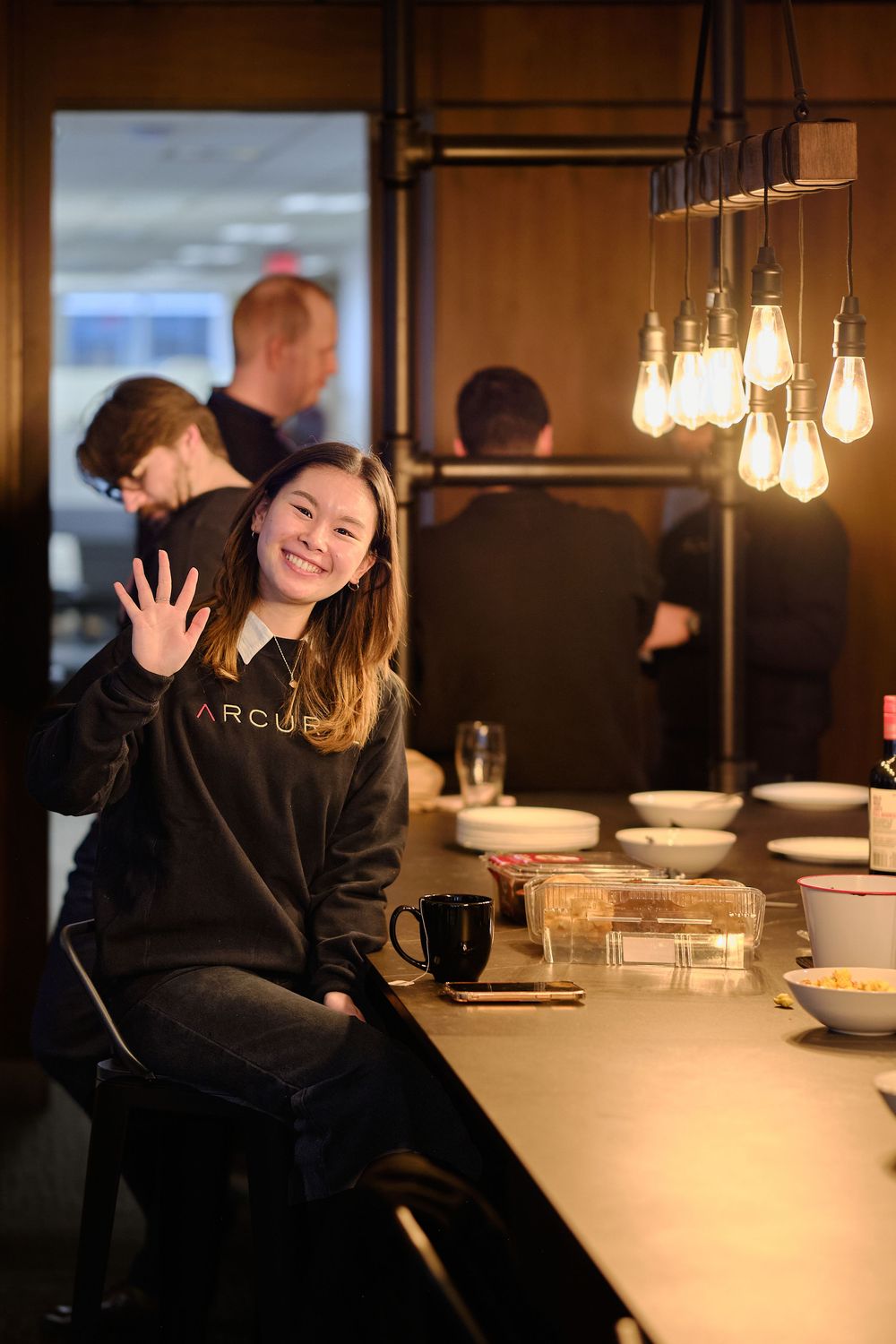 Person enjoying a cozy evening at a modern restaurant bar with warm lighting and minimalist decor.