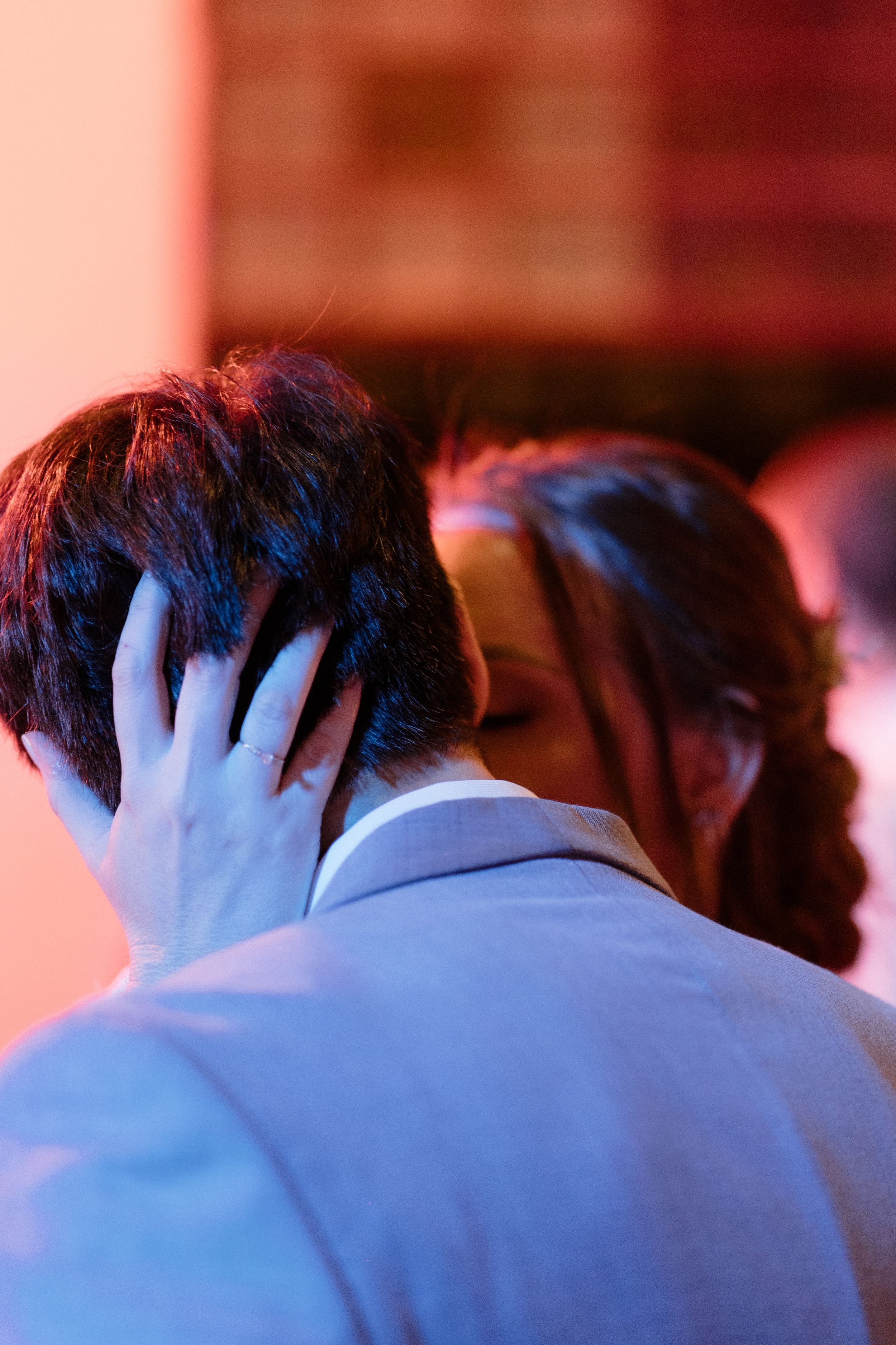 Abstract close-up view of hair and shoulders in blue tinted lighting.