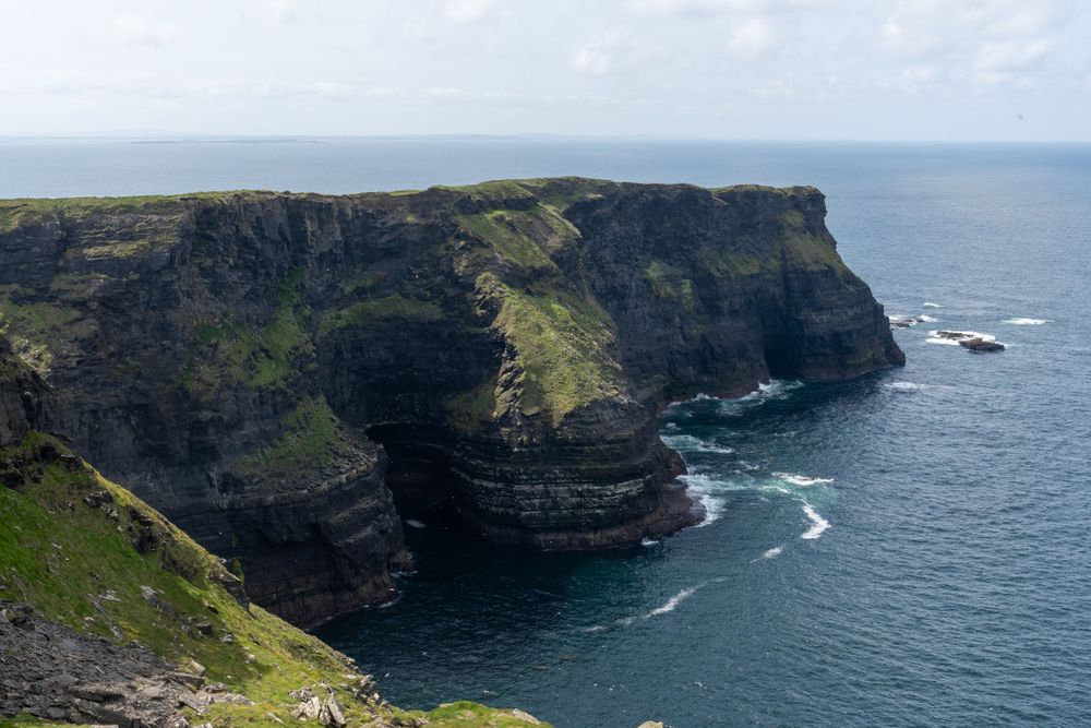 Dramatic coastal cliffs rise above the blue Atlantic Ocean at the Cliffs of Moher in Ireland.