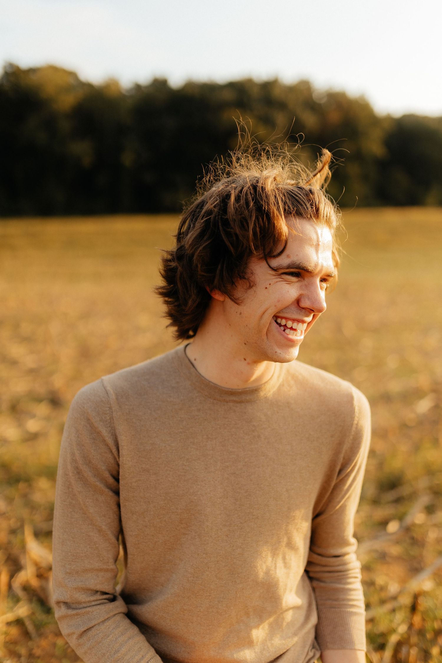 Black and white portrait of smiling young man in white t-shirt against dark background.