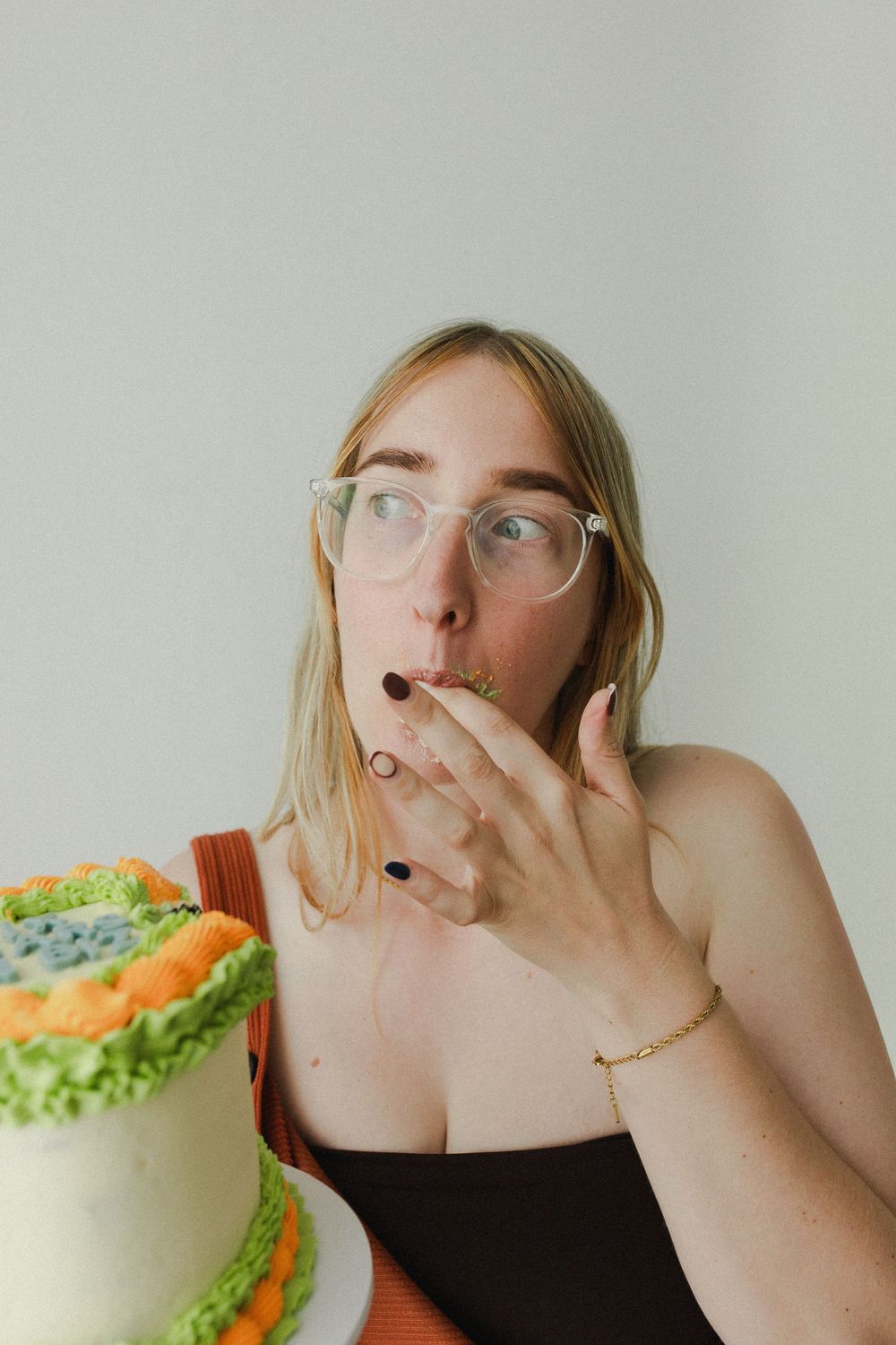 Woman eating a cake with frilly orange and green icing