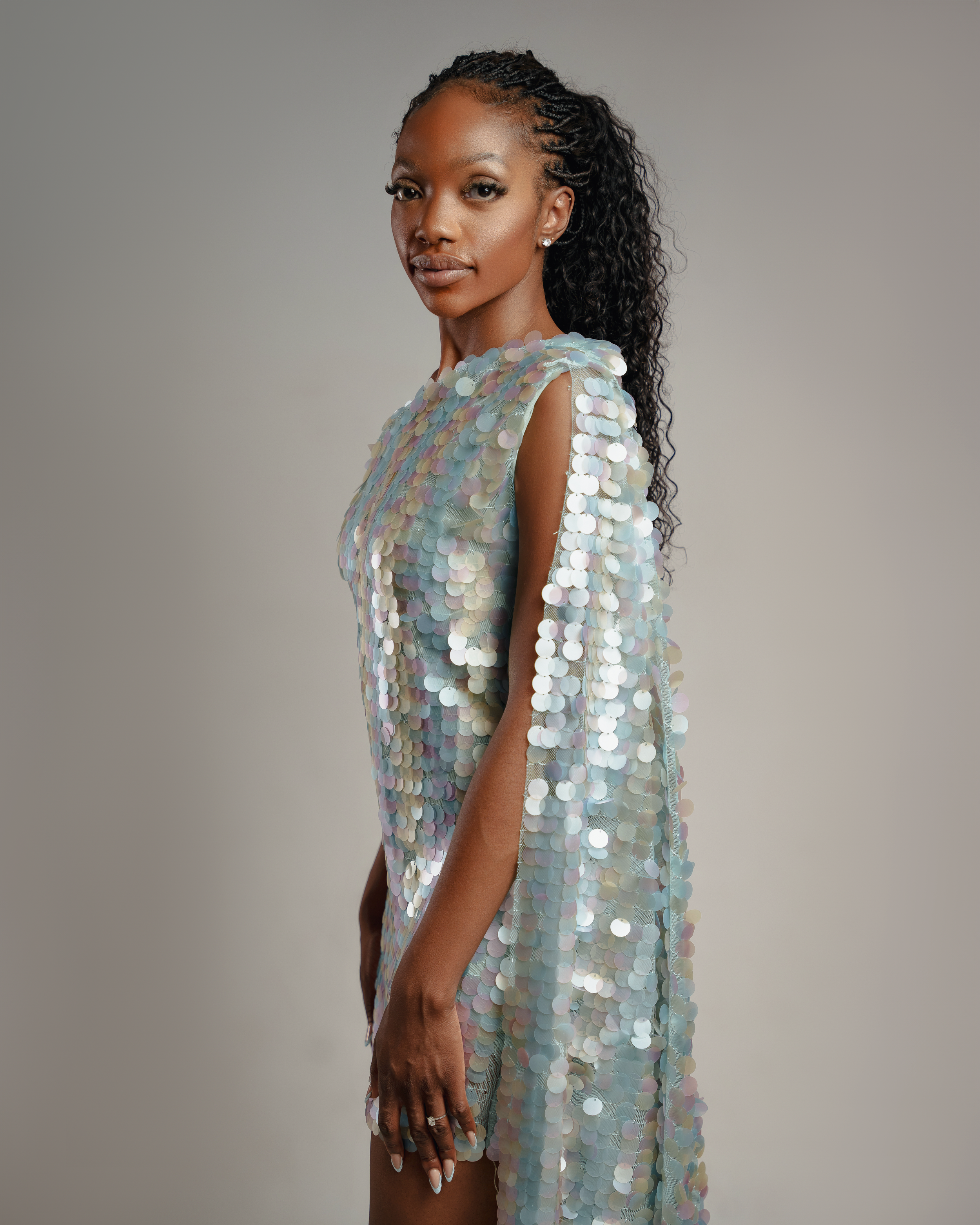 Fashion model poses in a shimmering light blue sequined dress against a neutral backdrop.